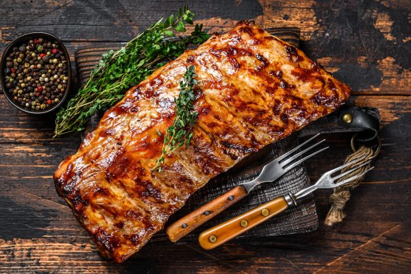 BBQ grilled pork spare ribs on a cutting board. Wooden background. Top view